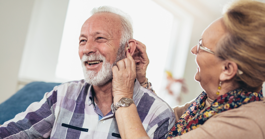 Women helping man with hearing aid